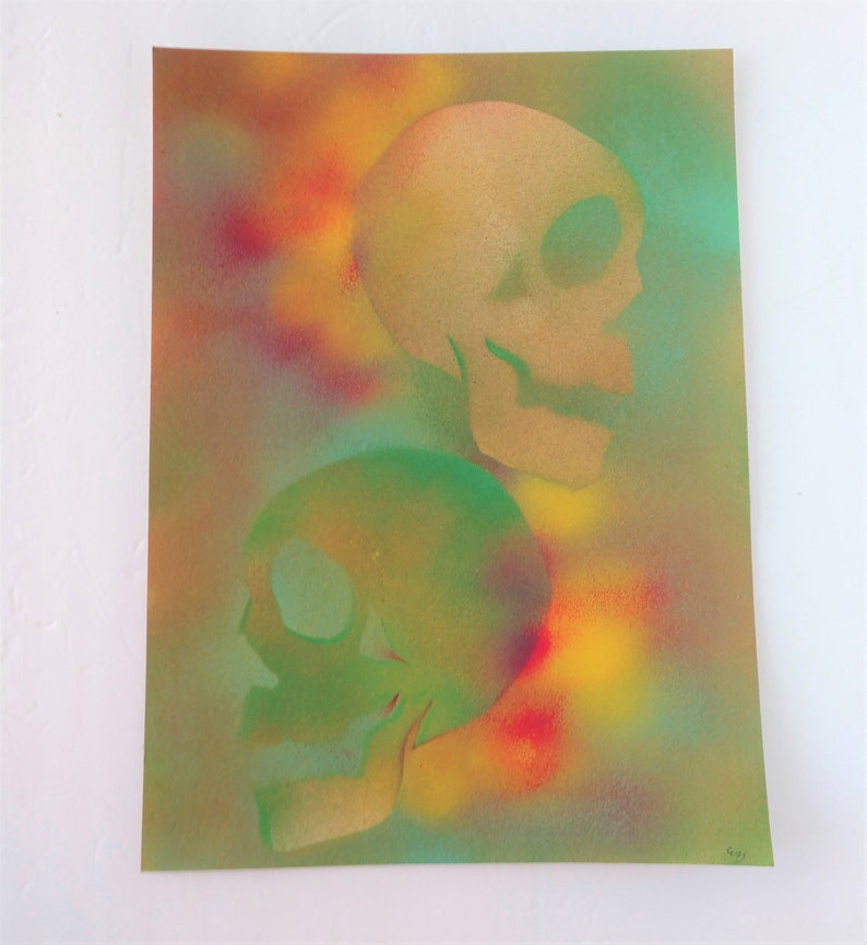 May include: Two skulls are painted in green and gold on a background of yellow, orange, red, and blue spray paint.