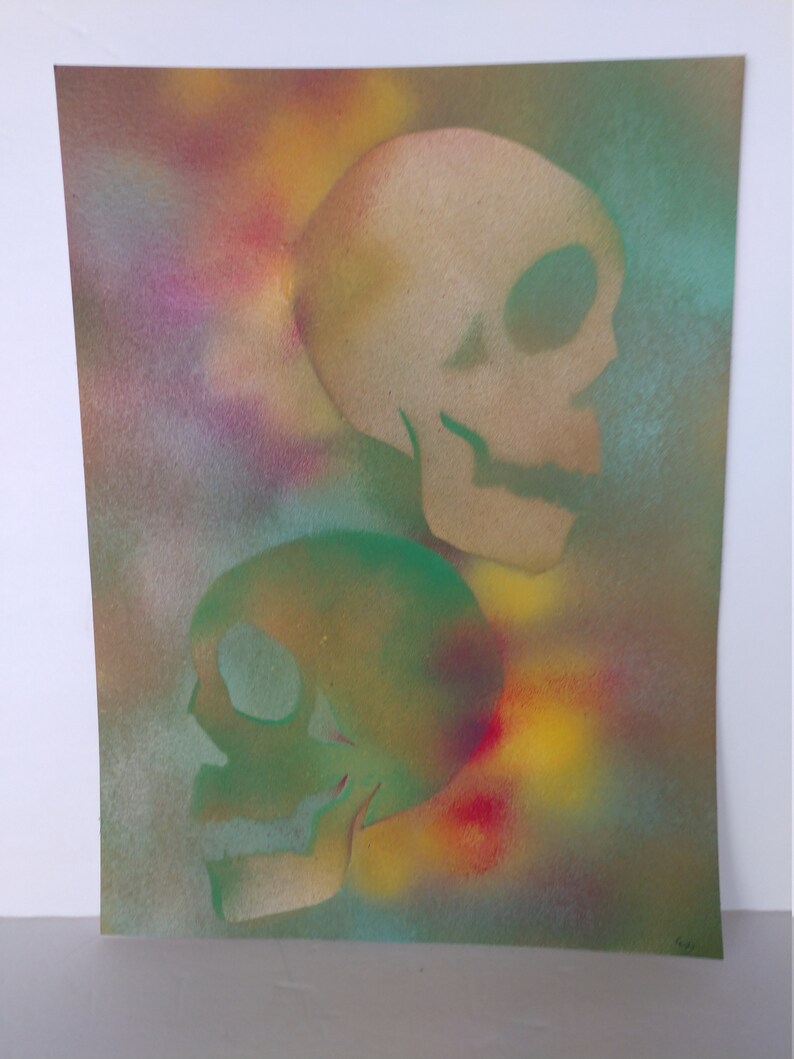 May include: Two skulls painted in a spray paint technique on a canvas background. The top skull is beige and the bottom skull is green. The background is a mix of yellow, red, blue, and green.
