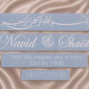 Könnte beinhalten: Vier rechteckige hellblaue Vinyl-Aufkleber mit weißer Schrift. Der oberste Aufkleber zeigt arabische Kalligrafie. Der zweite zeigt die Namen Navid & Shaista in Schreibschrift. Der dritte enthält "And We created you in pairs" Qur'an (78:8). Der unterste zeigt 26/07/2026.
