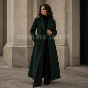 May include: A long, dark forest green wool-blend coat featuring a double-breasted front, wide lapels, and long sleeves. The coat is worn over a black turtleneck jumper and black trousers. The text Custom Wear Studio PK is visible.