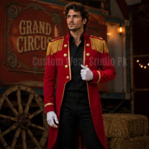 May include: A red long-sleeve military-style coat featuring gold fringe epaulettes, gold-tone buttons, and gold trim along the front opening and cuffs. The coat is worn over a black button-down shirt and black trousers, paired with white gloves.