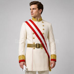 Könnte beinhalten: Eine cremefarbene Tunika im Militärstil mit einem Stehkragen mit Goldstickerei, goldenen Knöpfen und roten Manschetten. Eine rot-weiße Schärpe wird diagonal über der Brust getragen, kombiniert mit einem goldenen Gürtel mit schwarzen Streifen.