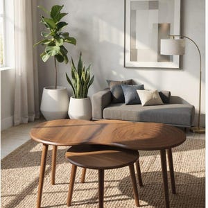May include: A set of two nesting coffee tables made of dark brown wood. The larger table features a smooth surface on one side and a circular, grooved pattern on the other. Both tables have three tapered legs and a rounded, organic shape.