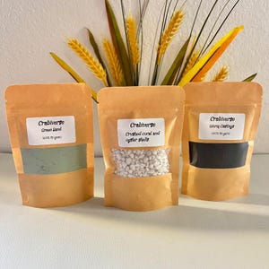 May include: Three brown paper pouches with clear windows containing soil additives. The left pouch is labeled Crabiverse Green Sand, the center pouch is labeled Crabiverse Crushed coral and oyster shells, and the right pouch is labeled Crabiverse Worm Castings.