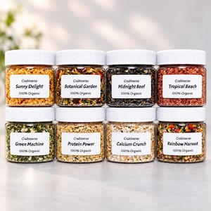 May include: Eight clear plastic jars with white lids containing organic food blends. Labels read: Sunny Delight, Botanical Garden, Midnight Reef, Tropical Beach, Green Machine, Protein Power, Calcium Crunch, and Rainbow Harvest, all marked 100% Organic.