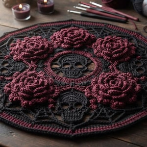 May include: A circular crochet doily featuring a black and dark red color scheme. The design incorporates a central skull motif surrounded by four three-dimensional dark red roses and alternating black skull patterns arranged in a radial mandala layout.