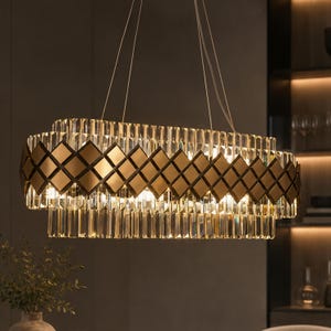 May include: A rectangular chandelier with a gold-colored metal frame and clear crystal accents. The design features a grid of diamond shapes and vertical crystal rods, suspended from thin wires. The light fixture is illuminated, casting a warm glow.