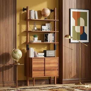 May include: A tall wooden wall-mounted shelving unit with four open shelves and a lower cabinet featuring two sliding doors. The unit holds books, a globe, a small Eiffel Tower model, framed photos, a potted plant, and a rectangular speaker.
