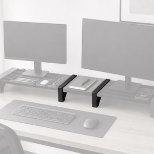 May include: A gray desk setup with two computer monitors on matching monitor stands. The stands have built-in storage for office supplies. A keyboard and mouse sit on a gray desk mat.