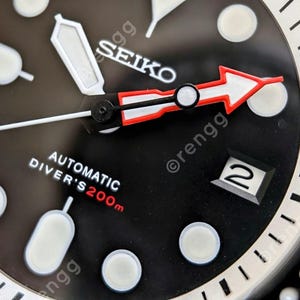 Peut inclure: Gros plan d'une montre de plong&eacute;e automatique Seiko noire. Le cadran de la montre comporte des index blancs, une fen&ecirc;tre de date et une aiguille des secondes en forme de fl&egrave;che rouge et blanche. La montre est &eacute;tanche &agrave; 200 m.