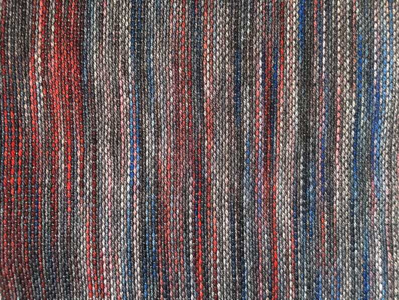 K&ouml;nnte beinhalten: Nahaufnahme eines gewebten Stoffes mit einem gestreiften Muster in Rot-, Blau-, Grau- und Wei&szlig;t&ouml;nen.