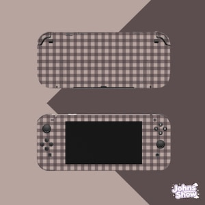 Può includere: Una console di gioco portatile con un motivo a quadretti vichy marrone e bianco sulla parte anteriore e posteriore. Il dispositivo include uno schermo centrale, un pad direzionale, due levette analogiche e quattro pulsanti d'azione X, Y, A e B.