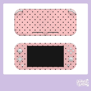 May include: Pink Nintendo Switch Lite console and top cover with a black polka dot pattern. The console has a black screen, white buttons, and a directional pad. The top cover has a matching polka dot design. The image is set against a white background.