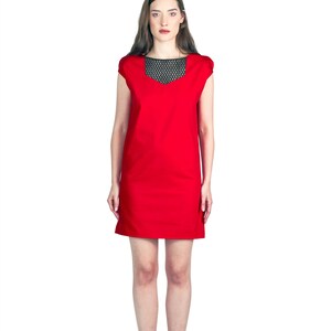 May include: A woman wearing a red sleeveless dress with a black mesh neckline and black heeled sandals.