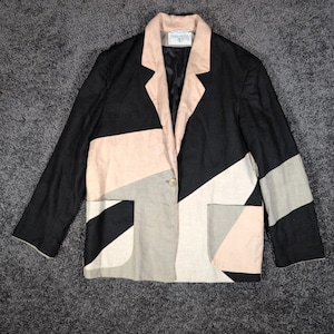 May include: A blazer featuring a color-blocked geometric pattern in black, beige, and soft pink. The jacket has a notched lapel, a single front button closure, and two patch pockets. The interior is lined with black fabric and includes a brand label.