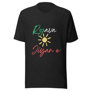 Könnte beinhalten: Dunkelgraues T-Shirt mit den Worten "Rojava Jiyan e" in grüner und roter Schrift, mit einer gelben Sonnengrafik. Das T-Shirt hat einen Rundhalsausschnitt und kurze Ärmel.