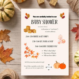 May include: A rectangular baby shower invitation card featuring autumn leaves, pumpkins, and wooden alphabet blocks. The text reads: You are cordially invited to our BABY SHOWER, followed by placeholders for date, location, address, and RSVP details.