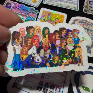 Op de afbeelding: Een holografische sticker met een groep ge&iuml;llustreerde personages met diverse haarkleuren en stijlen, gekleed in kleding ge&iuml;nspireerd op het begin van de jaren 2000. De sticker heeft een gestanste vorm en een glinsterend, veelkleurig effect.