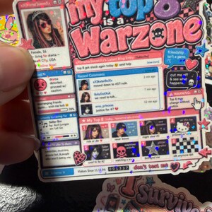 Op de afbeelding: Een holografische sticker met een social media profiel lay-out uit de jaren 2000 met de tekst "my top 8 is a WARZONE". Het ontwerp bevat een gebruikersavatar, een sectie voor recente reacties, een "My Top 8"-raster en een bezoekersteller op 001337.