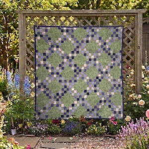 May include: A square quilt featuring a repeating lattice pattern of dark blue and light purple squares set against a mottled sage green background, finished with a solid dark blue border around the entire perimeter of the fabric piece.