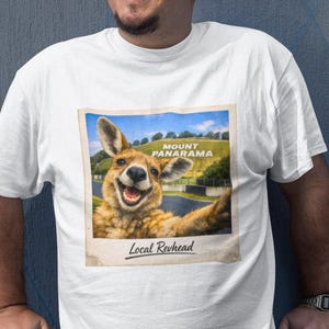 May include: A white t-shirt featuring a graphic print of a smiling kangaroo taking a selfie at Mount Panorama. The image is styled like a vintage polaroid photo with the text Mount Panorama visible on the hill and Local Revhead written below.