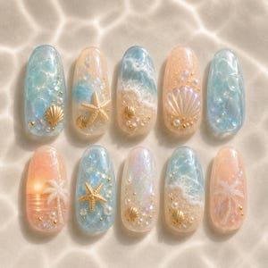 May include: A set of ten artificial nails with a beach theme. Each nail features a unique design with ocean waves, seashells, starfish, and palm trees, in shades of blue, peach, and gold. The nails are decorated with glitter and small pearls.
