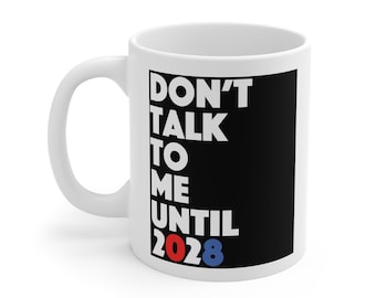 May include: A white ceramic mug featuring a black rectangular graphic on the side. The text "DON'T TALK TO ME UNTIL" is printed in bold white capital letters, followed by the year "2028" with the "20" in red and the "28" in blue.