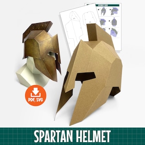 May include: Two papercraft Spartan helmets, one with a metallic bronze finish and one in plain tan cardstock, displayed alongside a printed assembly guide. An orange circular icon with a white downward arrow and the text PDF, SVG is visible.