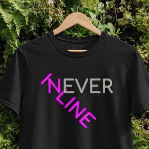Può includere: Una t-shirt nera a maniche corte con la scritta NEVER in grigio e LINE in rosa acceso. La parola NEVER è posizionata orizzontalmente, mentre la parola LINE è orientata in diagonale e interseca la prima lettera della parola NEVER.