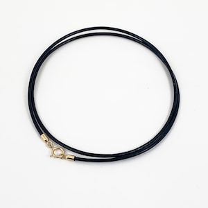 Puede incluir: Un collar de cuero azul oscuro con un cierre dorado. El collar tiene un diseño simple y elegante, perfecto para el uso diario. El collar mide aproximadamente 40 cm de largo.
