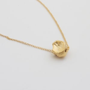 May include: A gold chain necklace with a single, textured, gold pendant.