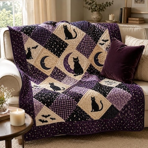May include: A quilted throw blanket featuring a patchwork design of black cats, crescent moons, and bats. The fabric pattern alternates between cream, purple, and black squares with gingham and celestial motifs, finished with a dark purple border.