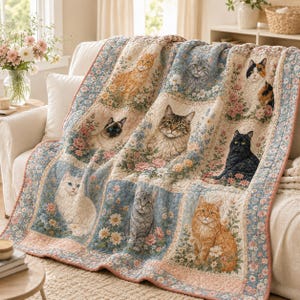 May include: A quilted throw blanket featuring a patchwork design of various cat breeds surrounded by floral patterns in shades of blue, pink, and cream. The cats include orange, tabby, Siamese, calico, black, and white varieties.