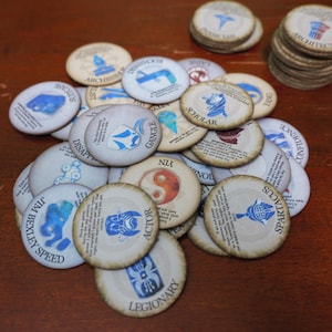 May include: A collection of circular game tokens with off-white surfaces and distressed brown edges. Each token features a unique blue or multi-coloured graphic icon, a printed title such as Actor, Legionary, or Scholar, and small black text descriptions.
