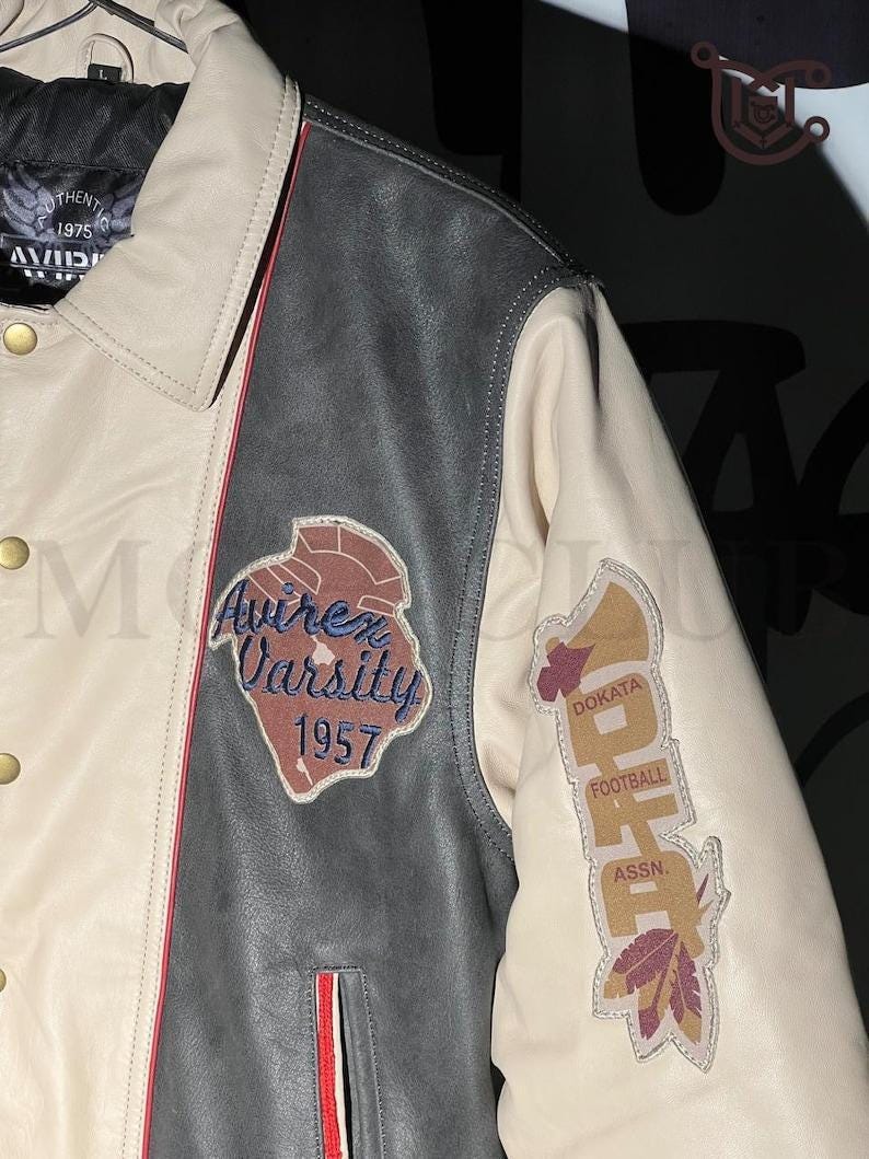 May include: A cream, black, and red leather varsity jacket with embroidered patches. The jacket features the text "Avirex Varsity 1957" and "Dokata Football Assn."