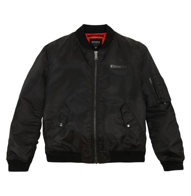 May include: Black bomber jacket with a zip-up front, ribbed cuffs, and a collar. The jacket has a small pocket on the left sleeve and a red lining visible at the collar. The brand name "AVIREX" is displayed on the chest.