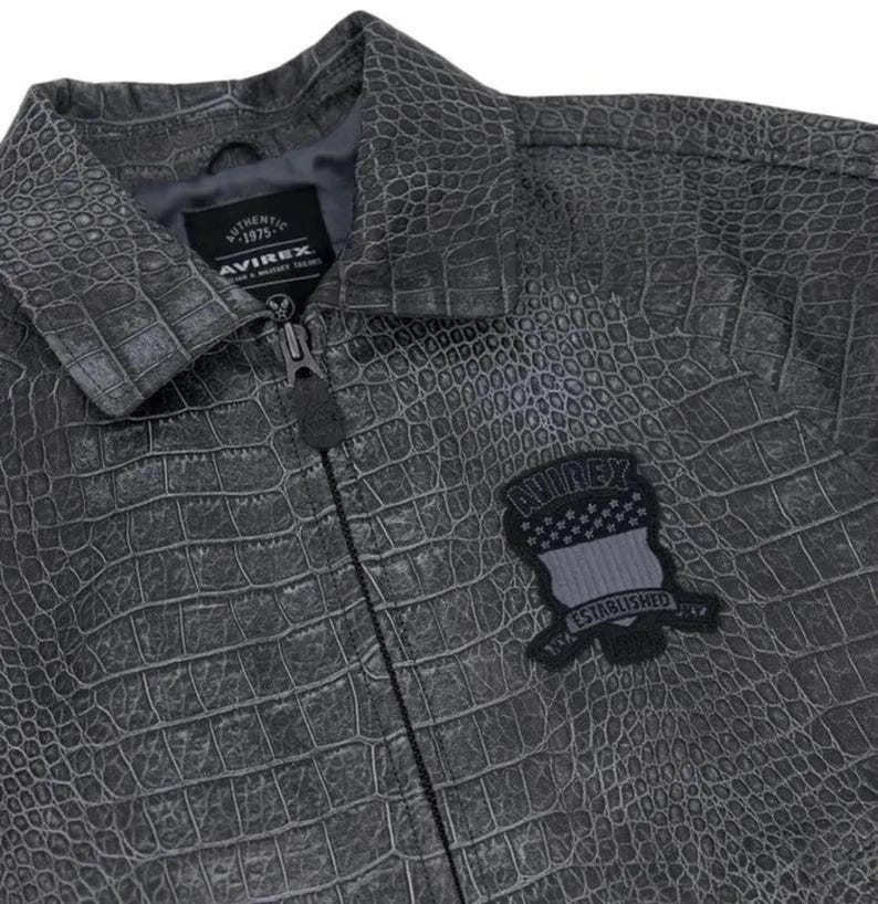 Pode incluir: Casaco cinzento texturizado com padr&atilde;o de pele de crocodilo. O casaco tem fecho de correr e um pequeno patch com o nome da marca e o texto "ESTABLISHED". O casaco tem gola e forro cinzento escuro.