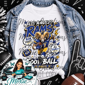 May include: A white t-shirt featuring a graphic of a Los Angeles Rams football player, a football, and the text Los Angeles Rams, Ram Pride, All Heart, and Football Los Angeles, CA, layered under a blue denim jacket with a watermark overlay.