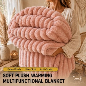 May include: A soft, dusty pink plush blanket with a thick, ribbed, channel-tufted texture. The blanket is folded and held, displaying a fuzzy, high-pile surface. Text on the image reads: Extra Plush, Ultra Soft, Anti-Static, SOFT PLUSH WARMING MULTIFUNCTIONAL BLANKET.