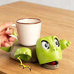 May include: A novelty turtle-shaped mug holder in green and tan. The turtle has large cartoon eyes and a wide mouth. A white mug with a brown rim sits on the turtle's back. The holder is on a wooden surface.