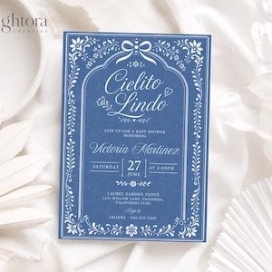 Könnte beinhalten: Eine rechteckige blaue Einladungskarte für eine Babyparty mit weißen floralen Bordüren, einem Schleifensymbol und dem Text Cielito Lindo, Join us for a baby shower honoring Victoria Martinez, Saturday 27 June at 2:00pm, Laurel Garden Venue.
