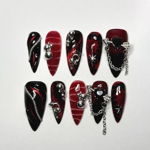 Unghie finte a catena con cuore da vampiro, design occhio di gatto bordeaux e nero, ciondoli a freccia argentata e perline cromate, set di unghie lunghe a stiletto