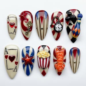 Könnte beinhalten: Zehn mandelförmige Nageldesigns mit Zirkus-Thema. Designs beinhalten Spielkartenfarben, einen Schlüssel, eine Taschenuhr, einen Clown, einen Stern, Popcorn und einen Pfeil mit dem Wort "ENTER". Farben sind Rot, Weiß, Blau und Schwarz.