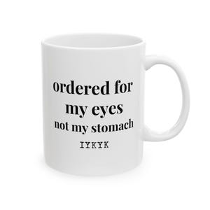 May include: White ceramic mug with a curved handle. The mug features black text that reads "ordered for my eyes not my stomach" and the acronym "IYKYK".