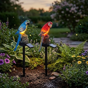 May include: Two solar-powered parrot garden stakes. One parrot is blue and yellow, the other is red and orange. Each bird sits atop a faux wood stump with a solar panel below. The stakes are in a garden setting with flowers and foliage.