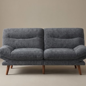 May include: A grey corduroy two-seater sofa with wooden legs. The sofa has a ribbed texture and a rounded arm design. The neutral colour and simple design make it suitable for various interior styles.