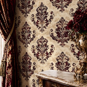 Puede incluir: Interior de una habitación con papel pintado damasco burdeos sobre un fondo crema. Una cortina burdeos a juego con detalles dorados está a la izquierda. Una mesa de madera ornamentada con tapa de mármol y adornos dorados está en primer plano.