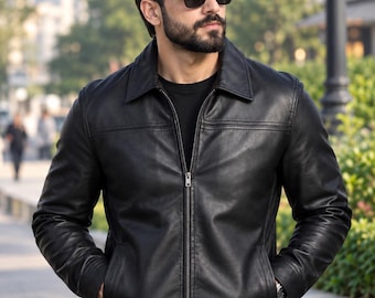 May include: A black leather jacket featuring a classic collar, a full-length front zipper closure, and two side pockets. The jacket has long sleeves with cuffs and horizontal seam detailing across the chest, worn over a plain black shirt.