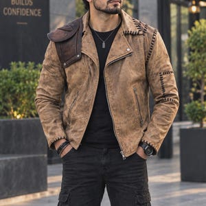 Puede incluir: Una chaqueta de cuero desgastado color canela con un parche marrón oscuro en el hombro, detalles de costura negra a lo largo del cuello y las mangas, cremallera frontal plateada, camiseta negra y pantalones cargo negros con cuello de solapa.