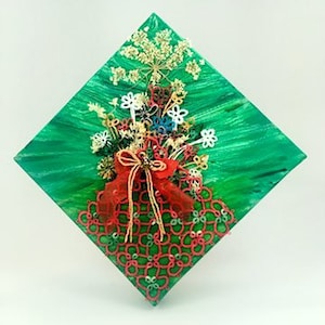 May include: A green canvas with a red, white, and gold lace design. The lace is in the shape of a bouquet of flowers with a red bow.